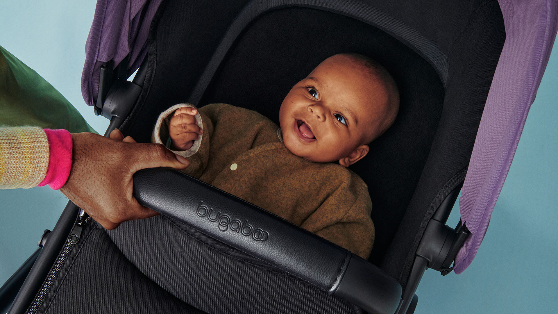 Baby smiling inside a Bugaboo bassinet.