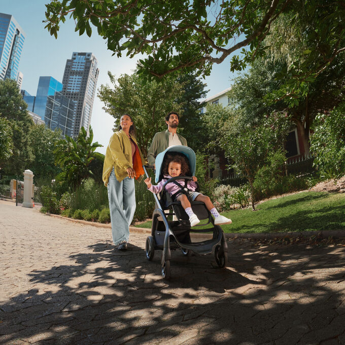 バガブー ドラゴンフライ ストローラーに座る幼児を連れて公園を散歩する母親と父親。