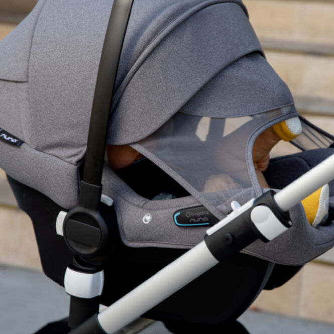 Cozy baby inside a Bugaboo Turtle Air by Nuna attached to a stroller, with the sun canopy fully extended.