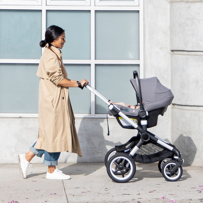 Woman pushing stroller with car seat attached