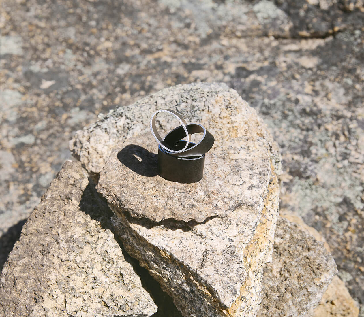 Some pieces of aluminium parts rest on a sun-bleached rock surface.