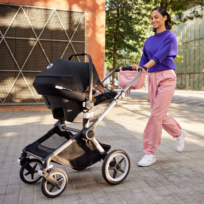 Mom strolling with baby in a Bugaboo Turtle Air by Nuna on a Bugaboo stroller.