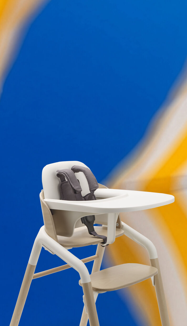 A blurred close-up of yellow and white striped beach umbrellas against a bright blue sky. With a Bugaboo Giraffe in the middle.