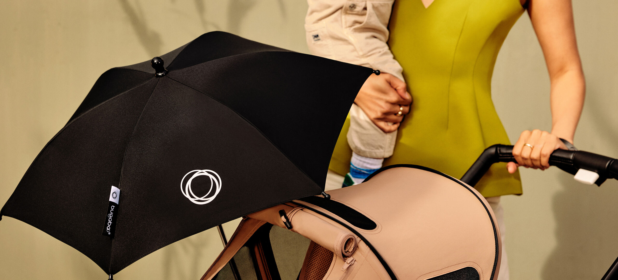 Mom pushing a Bugaboo stroller that has a parasol on it