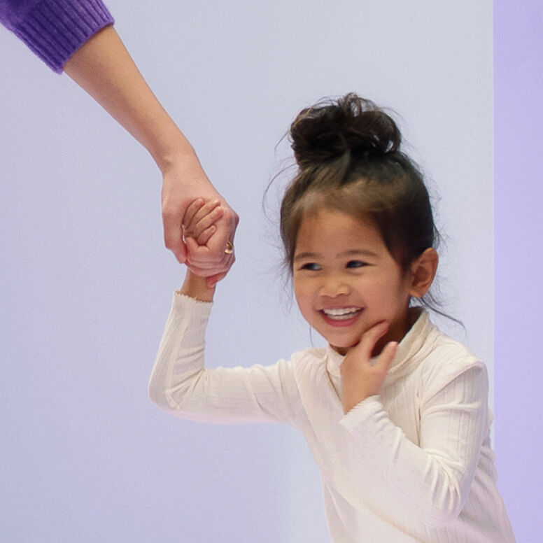 Smiling girl holding onto her parent's hand.