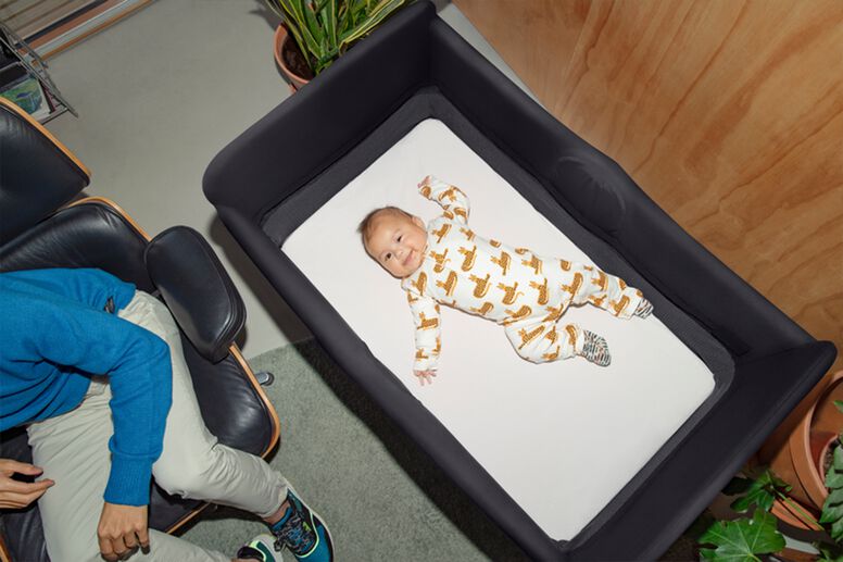 Baby resting in play yard with dad nearby