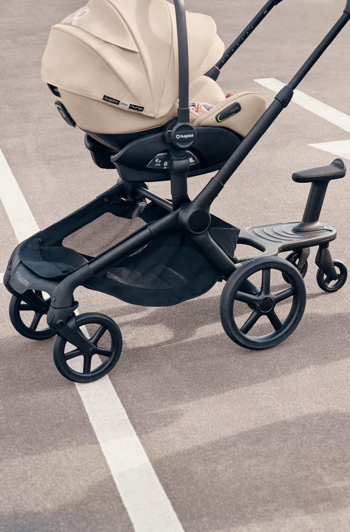 A Bugaboo pushchair with a Bugaboo Otter by Nuna car seat and a Bugaboo wheeled board attached