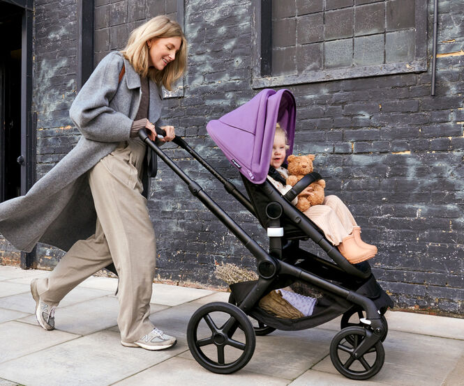 Mom and Dad taking baby in a Bugaboo stroller out for a walk in the park.