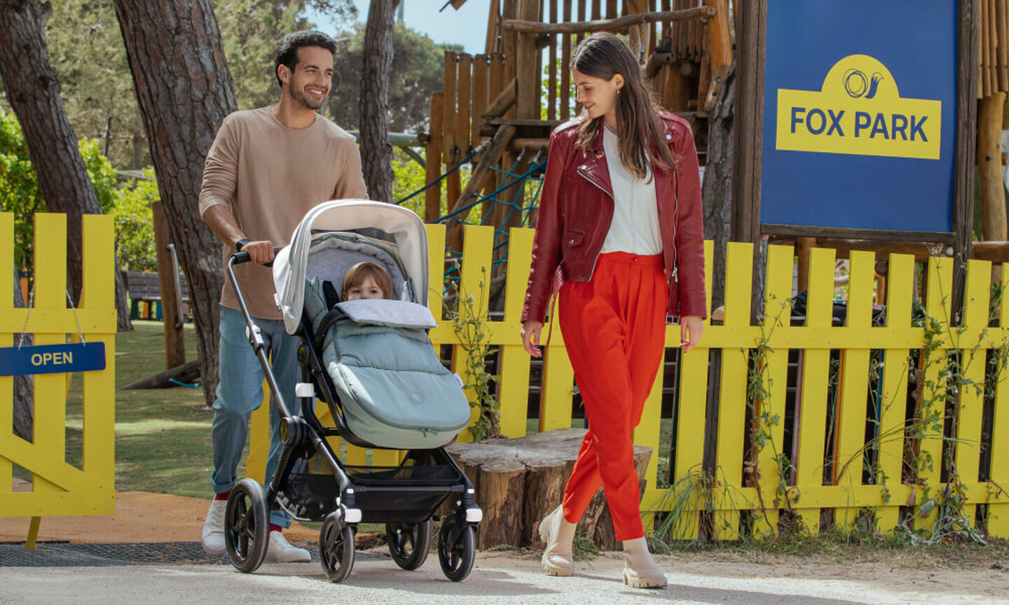 Parents taking baby to the park; the baby is snug in the Bugaboo Fox 3 with footmuff.
