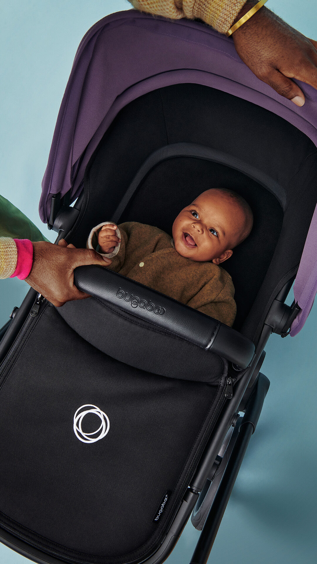 Baby smiling inside a Bugaboo bassinet.