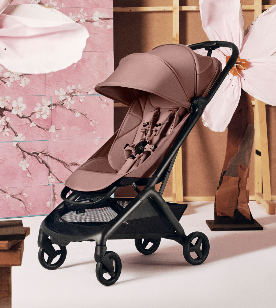 A Bugaboo Butterfly 2 with Dusty Pink fabrics is displayed in front of a soft pink background with large cherry blossoms.