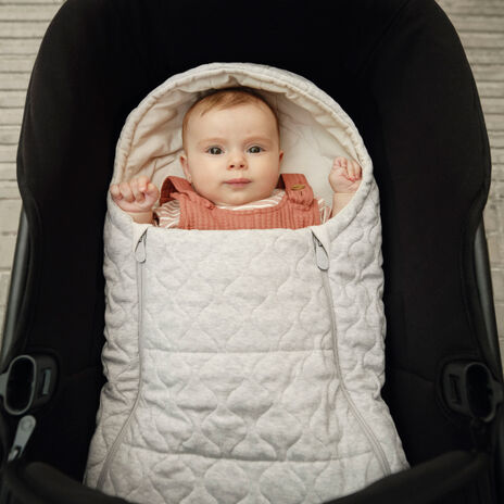 A baby safely nestled inside a white Bugaboo newborn inlay.