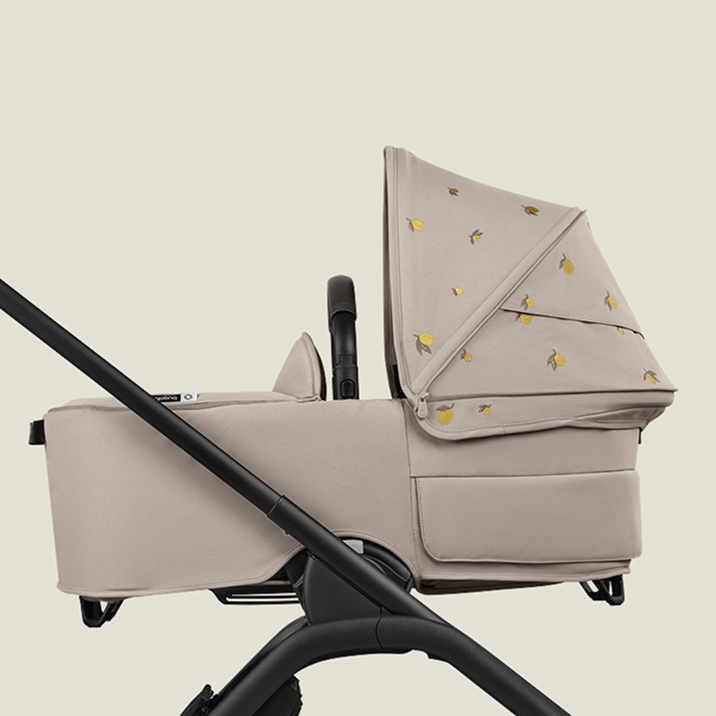 A Bugaboo Dragonfly bassinet stroller with Bugaboo X Konges Sløjd Limited Edition sun canopy, featuring Konges Sløjd's signature lemon print.