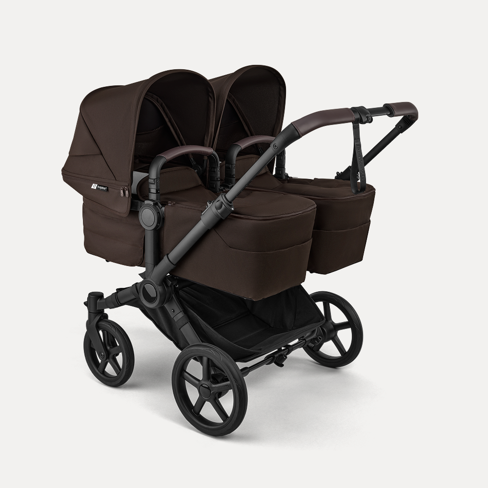 A Bugaboo Donkey 6 stroller in twin configuration, featuring two bassinets. The fabrics are in Cocoa Brown.