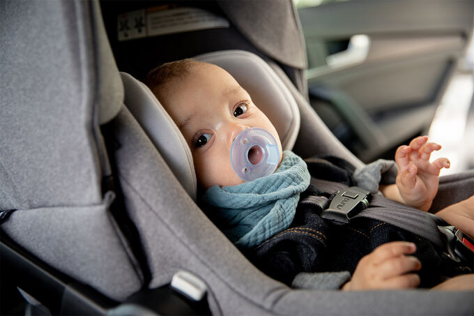 Infant in a car seat with a pacifier