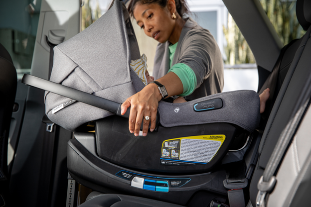A woman begins to lift the Bugaboo Turtle Air car seat, which is carrying a baby, out of the car