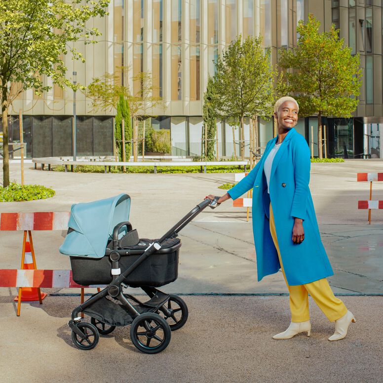 Mom walking her baby outside in a carrycot pushchair