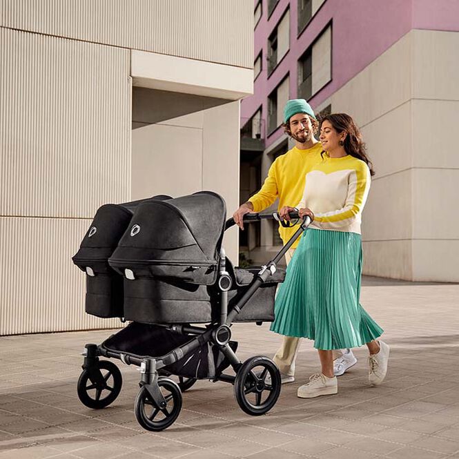 Parents strolling with their children in a Donkey 5 Twin bassinet stroller.