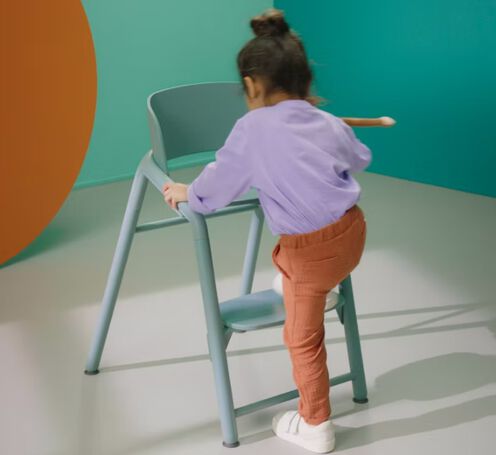 A child climbing onto a Bugaboo Giraffe chair.