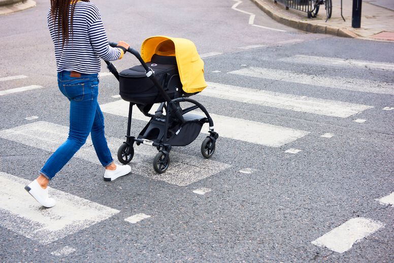 Mamá empujando un carrito por un paso de peatones