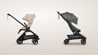 Compact folded Bugaboo stroller standing self-upright in a hallway next to a smiling toddler