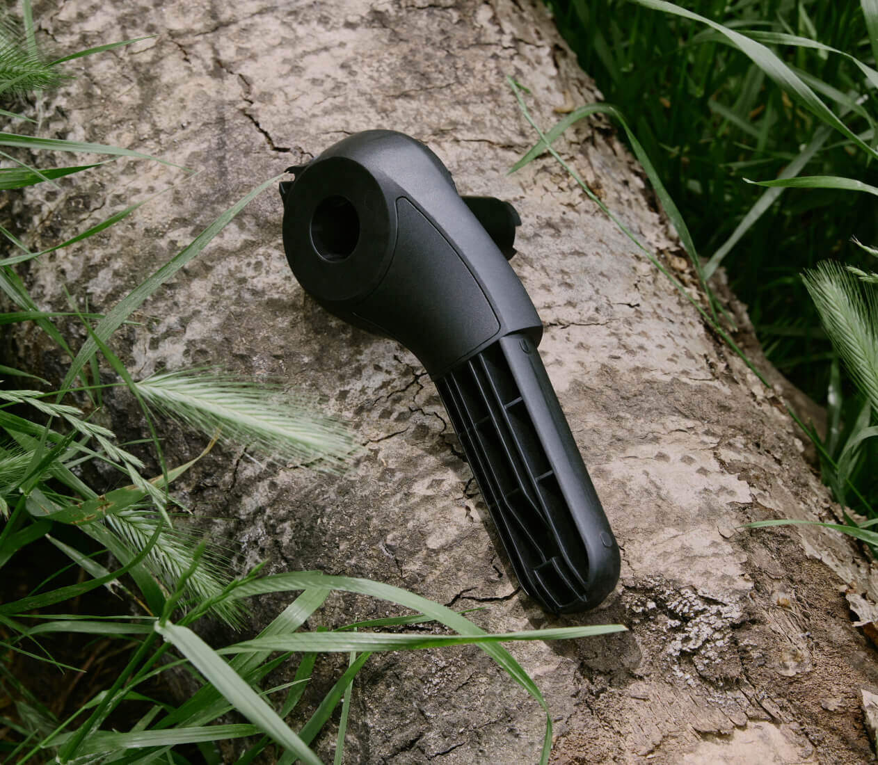 A component from a Bugaboo stroller rests on a tree trunk, surrounded by overgrown greenery.