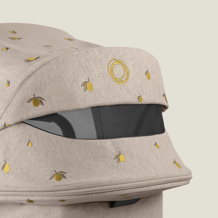 A close-up of Bugaboo X Konges Sløjd Limited Edition sun canopy with peek-a-boo window, showcasing the Bugaboo logo and Konges Sløjd's signature lemon print.