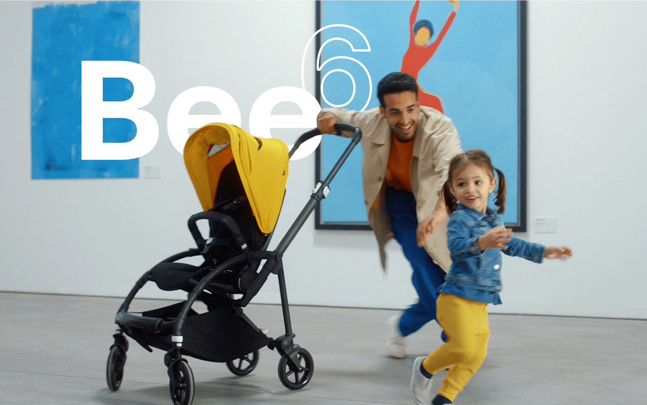 Dad and daughter playing in an art gallery with the Bugaboo Bee 6 in yellow sun canopy.