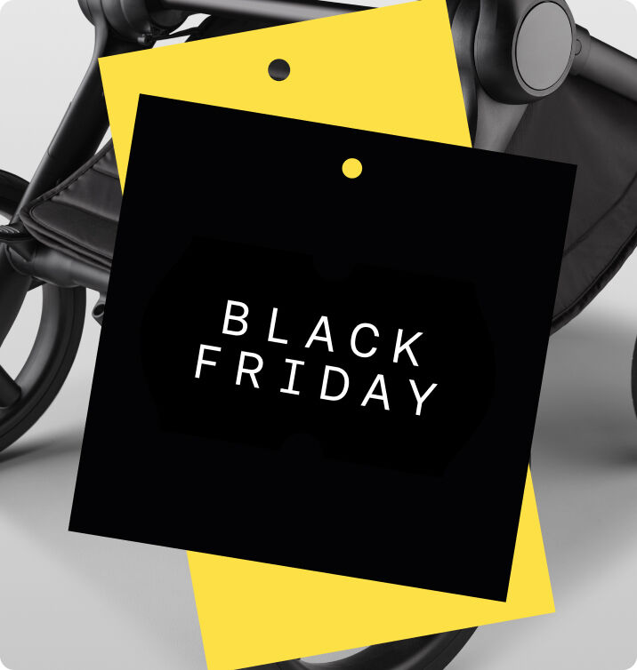 A black and white close up of the underseat basket and wheels of a Bugaboo stroller. The image is partially hidden behind two graphic tags in black and yellow.