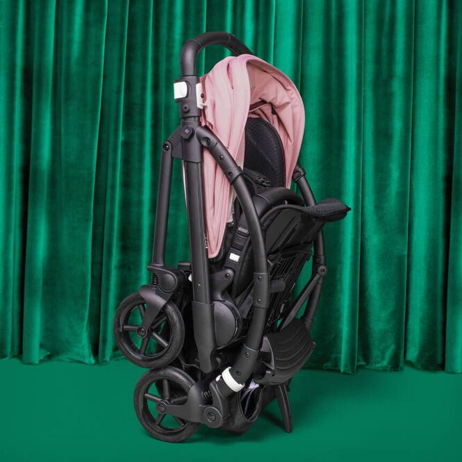 A self-standing folded Bugaboo Bee 6 with pink sun canopy.