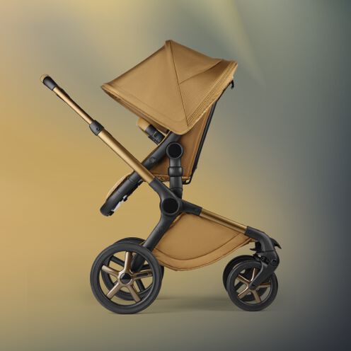 Side view of a Bugaboo Fox 5 Noir Limited Edition in Amber Glow, standing against an ethereal background with hues of yellow and green.
