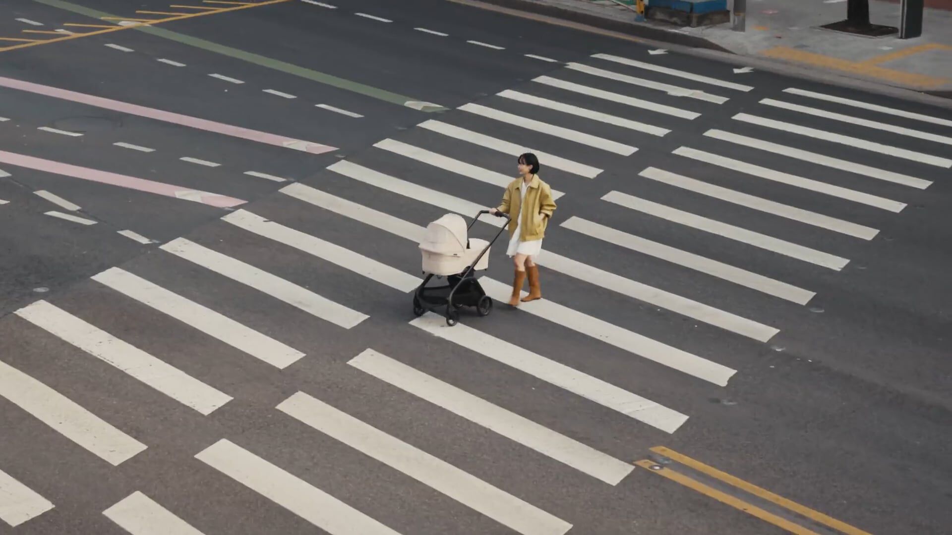 Video: A mom walks with a Bugaboo Dragonfly Plus stroller across a wide striped crosswalk on an empty city street.