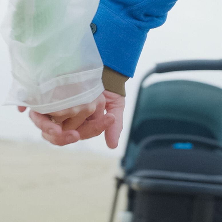 Parents holding hands in front of a Bugaboo stroller.