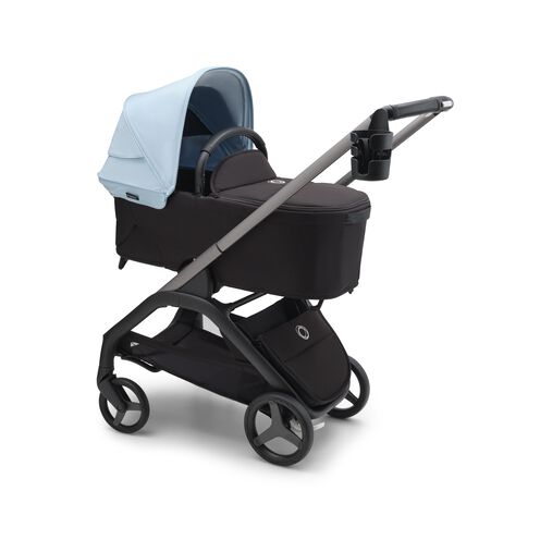 Mom pushing a Bugaboo double stroller, with a bottle in a cup holder attached to the stroller's handlebar.