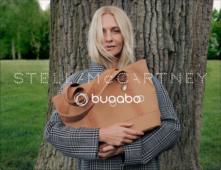 Poppy Delevingne leans against a large tree trunk while holding a Bugaboo x Stella McCartney tote bag.