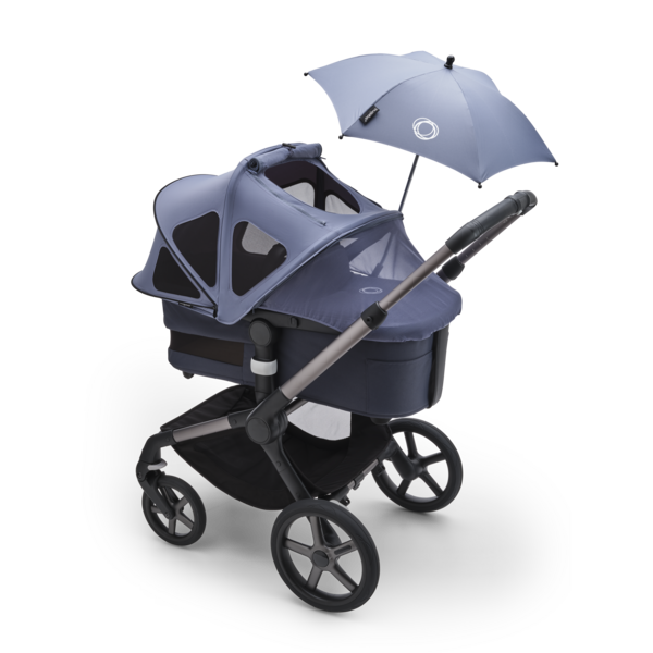 A Bugaboo stroller with Bugaboo parasol and Bugaboo breezy sun canopy fully extended to cover the bassinet.