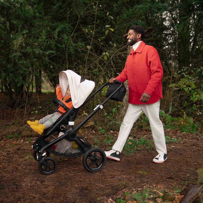 Dad and toddler enjoying a walk in the park with a Bugaboo stroller.