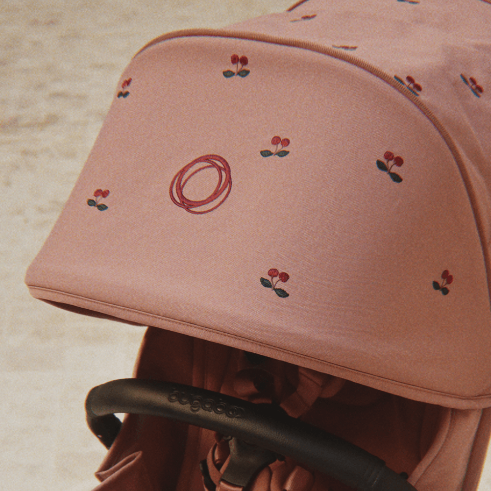 Bugaboo x Konges Sløjd 리미티드 에디션 썬 캐노피 클로즈업 사진. 더스티 핑크 색상의 패브릭에 체리 패턴 자수 디테일이 특징입니다.
