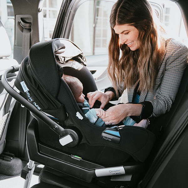 Mom putting baby in car seat