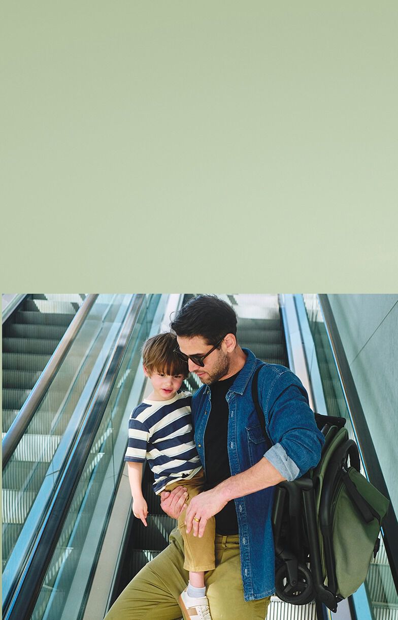 Dad holding baby and Bugaboo Butterfly 2 going down an escalator