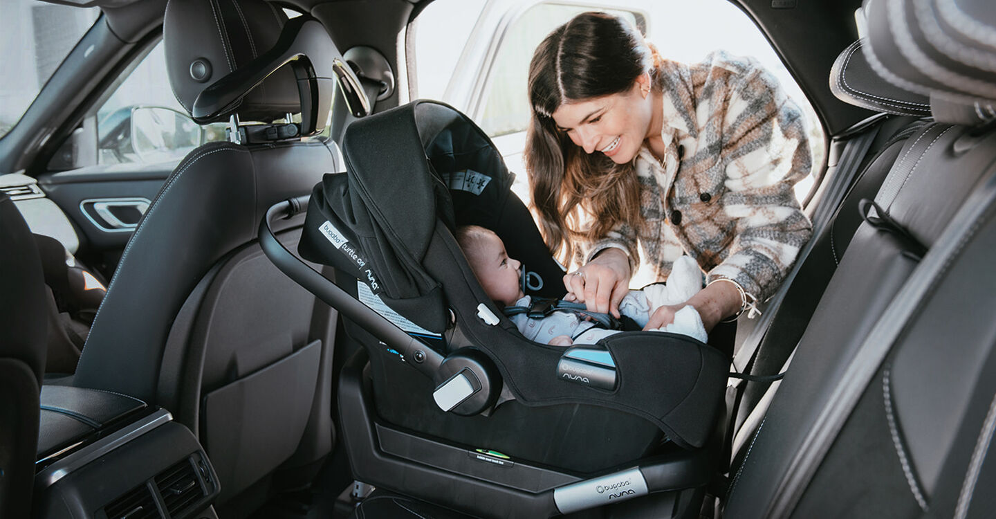 Mother strapping baby into car seat