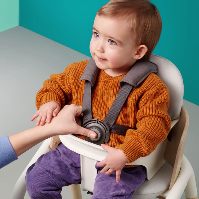 De gesp van de veilige vijfpuntsgordel vastmaken als de baby in de stoel zit.