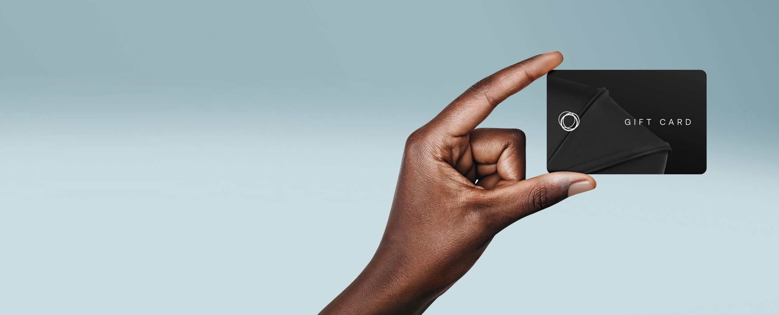 A hand holds up a Bugaboo gift card, on a gradient blue background.