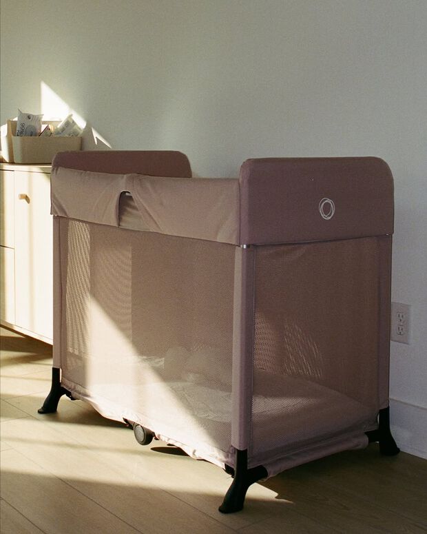 A Bugaboo Stardust travel cot in Desert Taupe fabrics sits in a well-lit, minimalistic hallway.