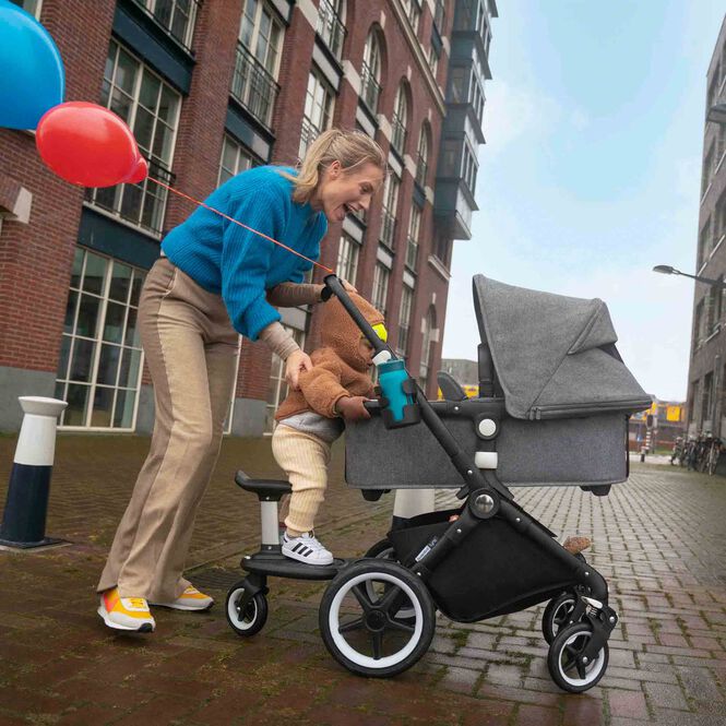 Mom and toddler cheering at an out of sight baby in a Bugaboo stroller.