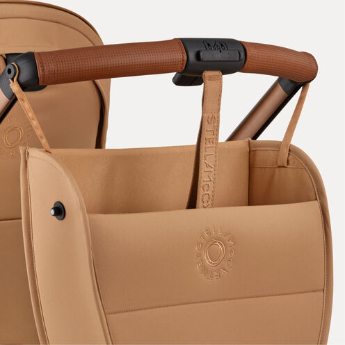 Gros plan sur le guidon de la poussette Bugaboo x Stella McCartney Special Edition et sur un sac latéral qui y est accroché, tous deux en tissu Tobacco Brown avec des accents Saddle Brown.