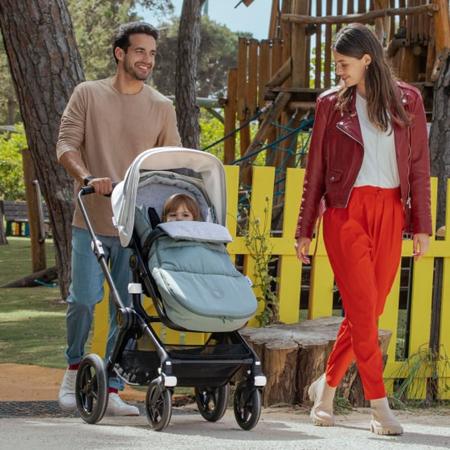 Parents taking baby to the park; the baby is snug in the Bugaboo Fox 3 with footmuff.