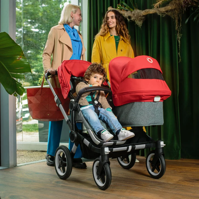 Two women pushing a toddler and a baby side-by-side in the Bugaboo Donkey Duo pushchair