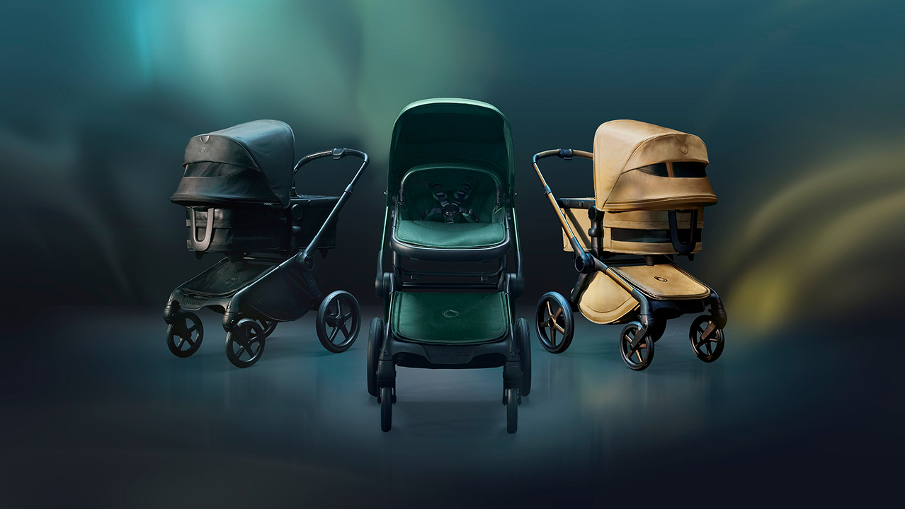 Three Bugaboo Fox 5 Noir Limited Edition strollers against a dark, ethereal background with hues of blue, yellow, and gold.