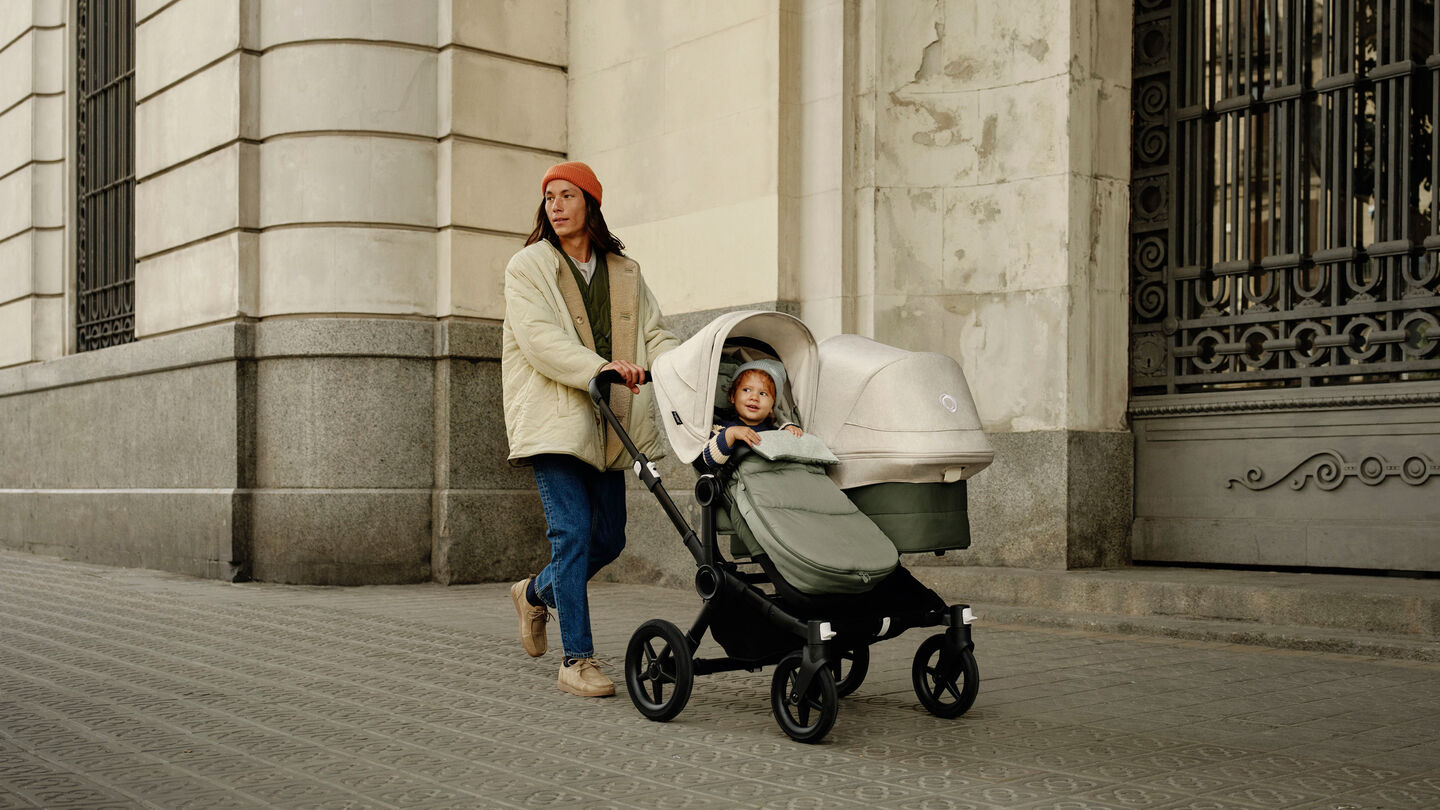 The Bugaboo Donkey 5 double stroller in forest green, with focus on the side-by-side seat and bassinet.